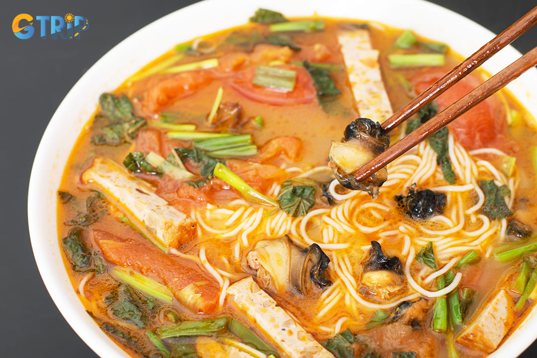 Bun oc features chewy freshwater snails in a tangy tomato and tamarind broth, served with vermicelli noodles and fresh herbs