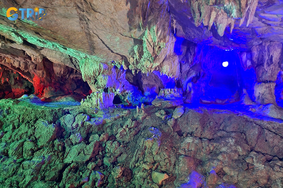 A display of stalactites and stalagmites illuminated by natural light and gentle artificial lighting