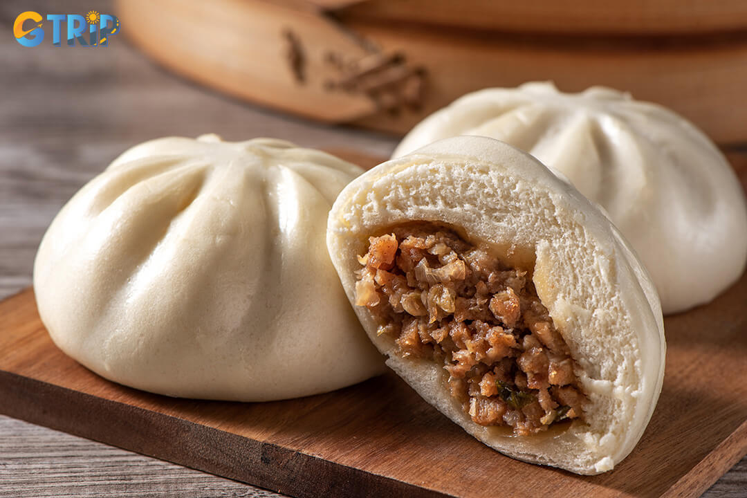 Banh bao are fluffy steamed buns filled with savory pork, mushrooms, vermicelli, and egg, a popular warm street breakfast in Saigon