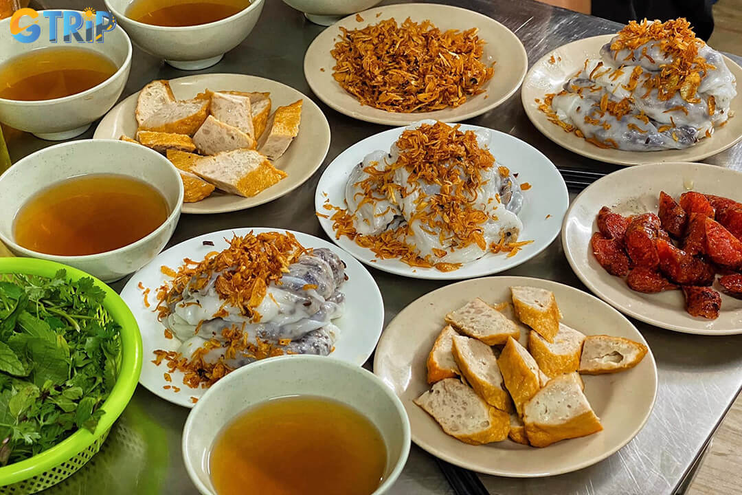 Banh cuon, Hanoi’s delicate steamed rice rolls, are filled with savory pork and mushrooms, served with tangy fish sauce for a light yet flavorful breakfast