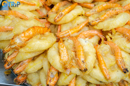 Banh tom is a Hanoi specialty of crispy sweet potato fritters with whole shrimp, enjoyed with fresh herbs and tangy nuoc cham