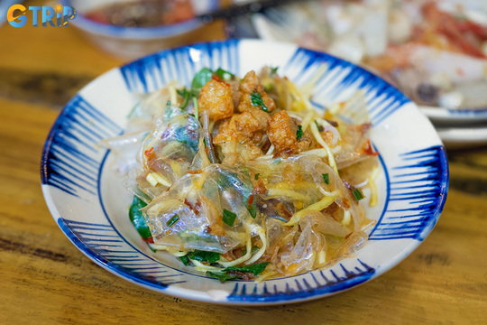 Banh trang tron is a Hanoi street snack of shredded rice paper mixed with dried beef, green mango, herbs, peanuts, chili, and tangy sauce for a vibrant mix of flavors