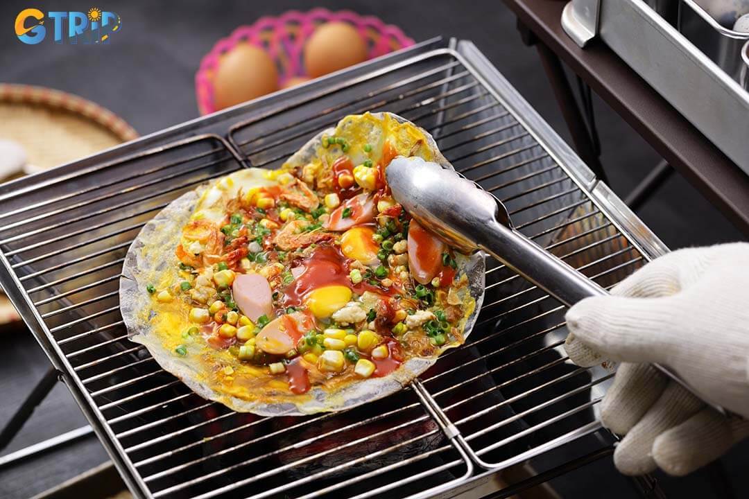 Beneath the bridge’s eastern side, lively street food stalls serve local favorites like banh trang nuong, offering a budget-friendly taste of everyday Da Nang life