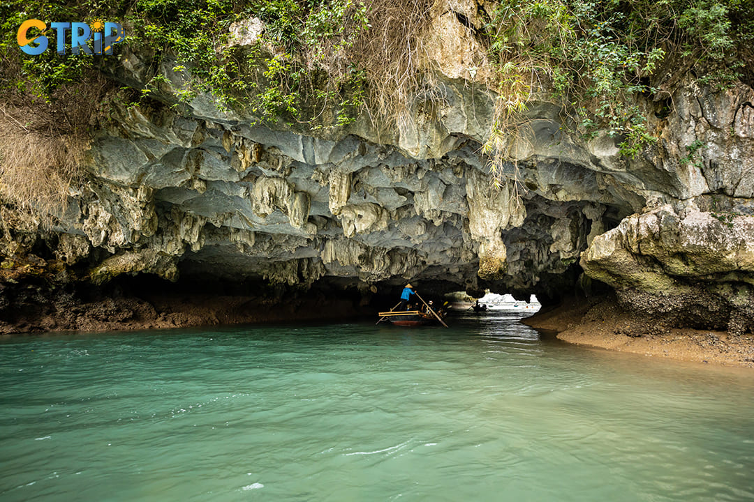 Beyond the cave's entrance lies a peaceful enclosed lagoon, surrounded by towering limestone cliffs