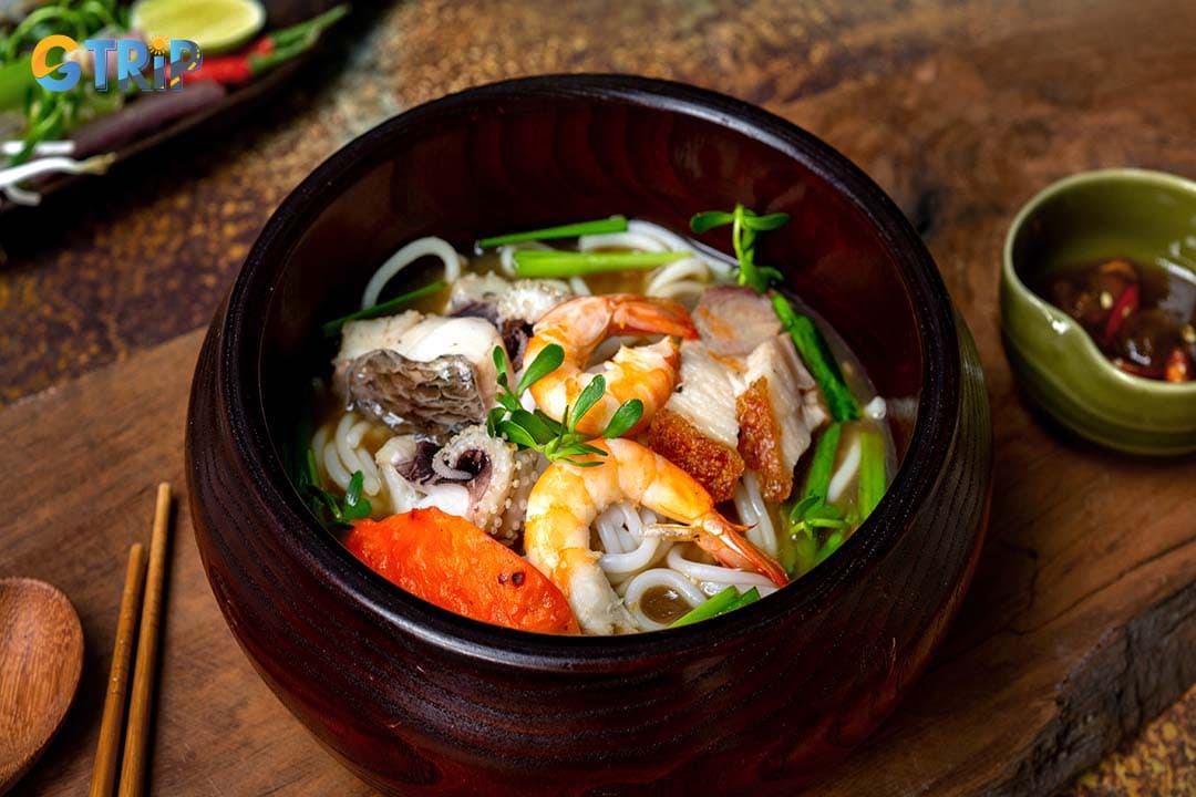 Bun Mam is a bold Mekong Delta noodle soup featuring a dark, pungent fermented fish broth, lavishly topped with pork belly, seafood, and fish