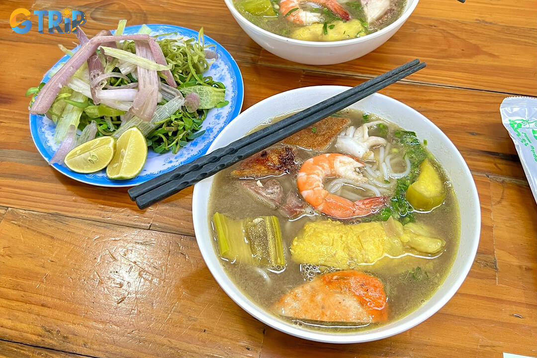 Bun Mam Phan Xich Long is well-balanced broth with tender squid, shrimp, and pork in a bustling Saigon street setting