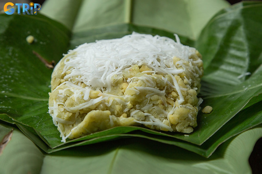 Com, Hanoi’s iconic autumn delicacy, features tender young green rice flakes with a soft, fragrant texture, often enjoyed with bananas or coconut