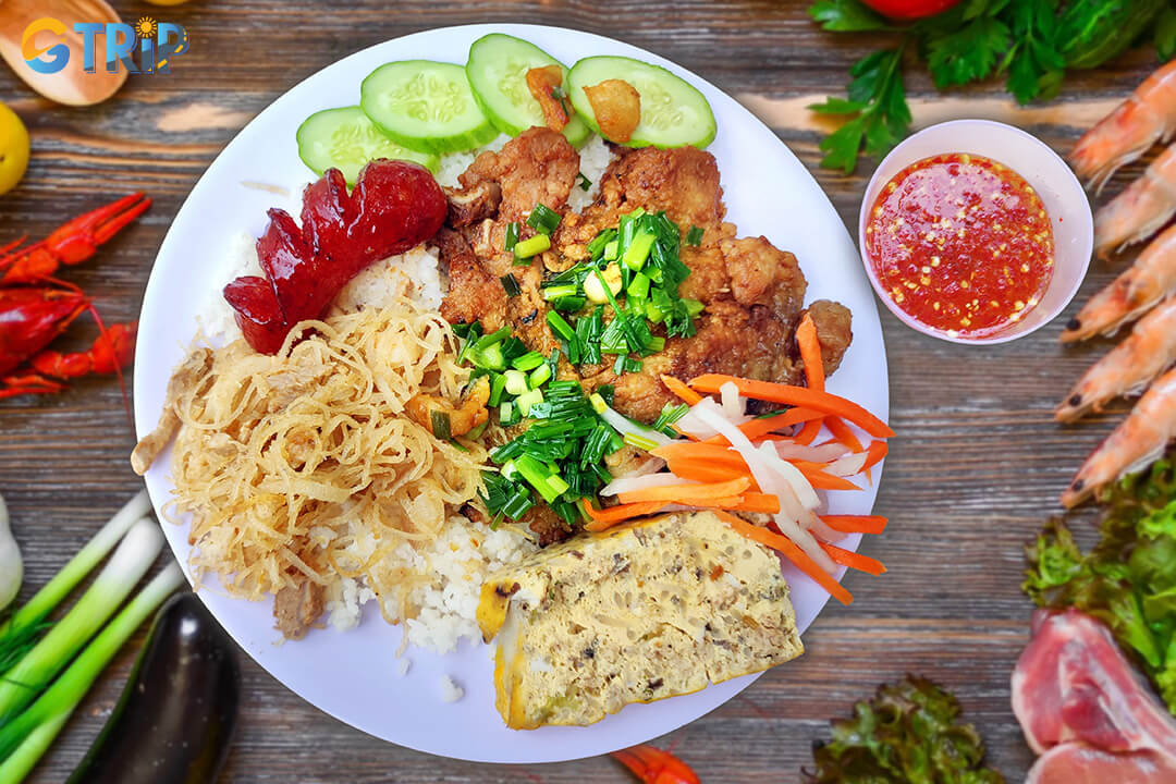 Com Tam is Saigon’s iconic broken rice dish, served with grilled pork, shredded pork skin, steamed egg, and tangy pickles for a flavorful, satisfying meal