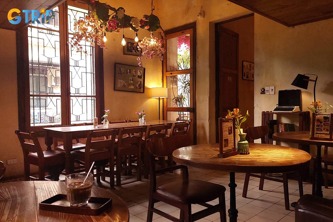 Housed in a restored French colonial townhouse, the cafe exudes a nostalgic ambiance with its vintage interiors, wooden furnishings, and floral-adorned balconies