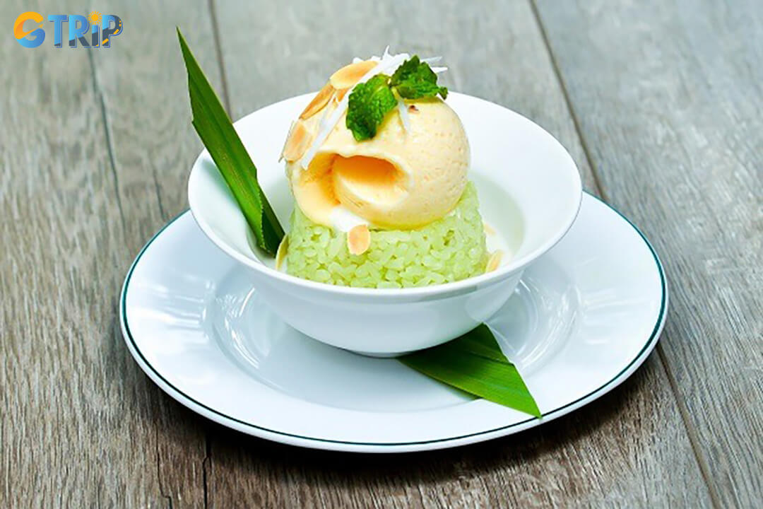 Kem xoi dua is a Ho Chi Minh City dessert of warm pandan sticky rice topped with coconut ice cream and crunchy garnishes, sweet, creamy, and refreshing