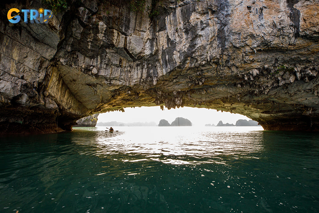 Luon Cave features a crescent-shaped archway leading to a hidden lagoon surrounded by towering limestone cliffs