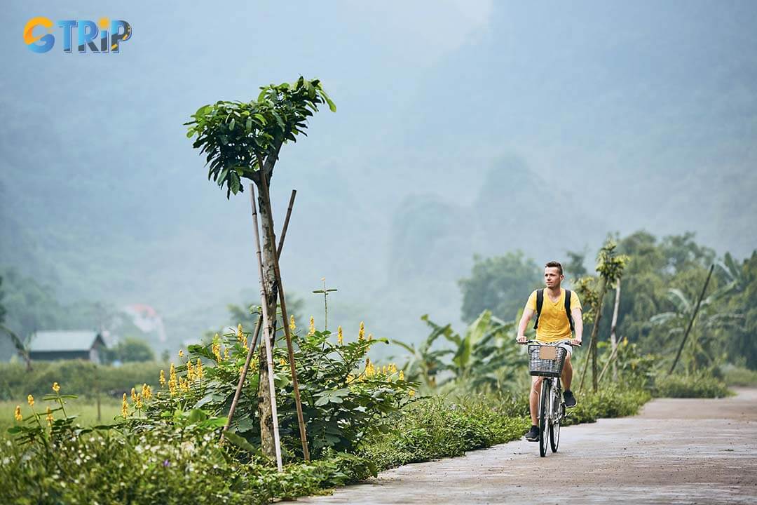 The man is very excited and riding a bicycle in the countryside in Ninh Binh