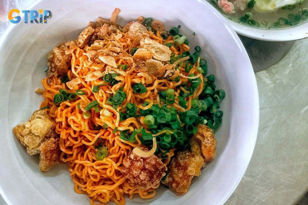 Mi Tron Muoi Ot is chewy instant noodles tossed in spicy chili salt and topped with quail eggs, dried beef or squid, corn, and citrus