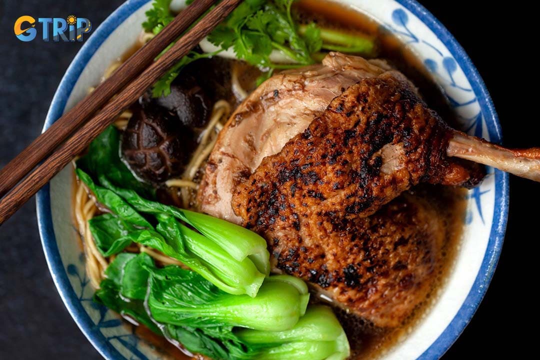 Mi Vit Tiem is a rich Chinese-influenced noodle soup featuring a whole duck leg braised until tender in a dark, savory-sweet herbal broth