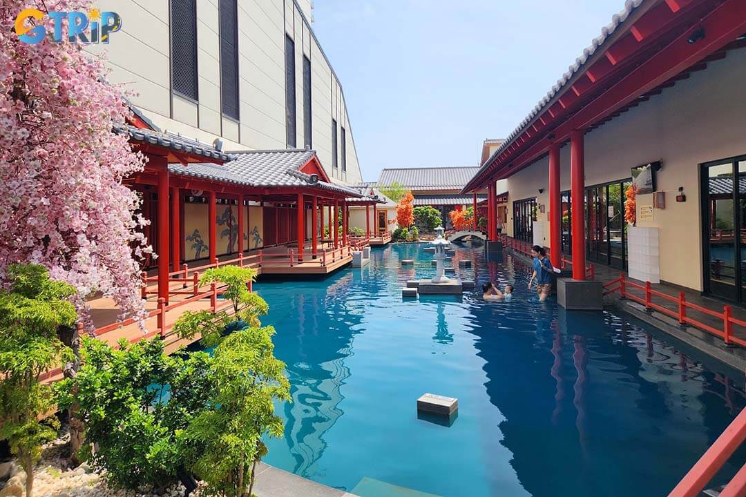 Mikazuki Water Park offering year-round family fun with themed rides, wave pools, and a Japanese onsen connected by a pedestrian bridge