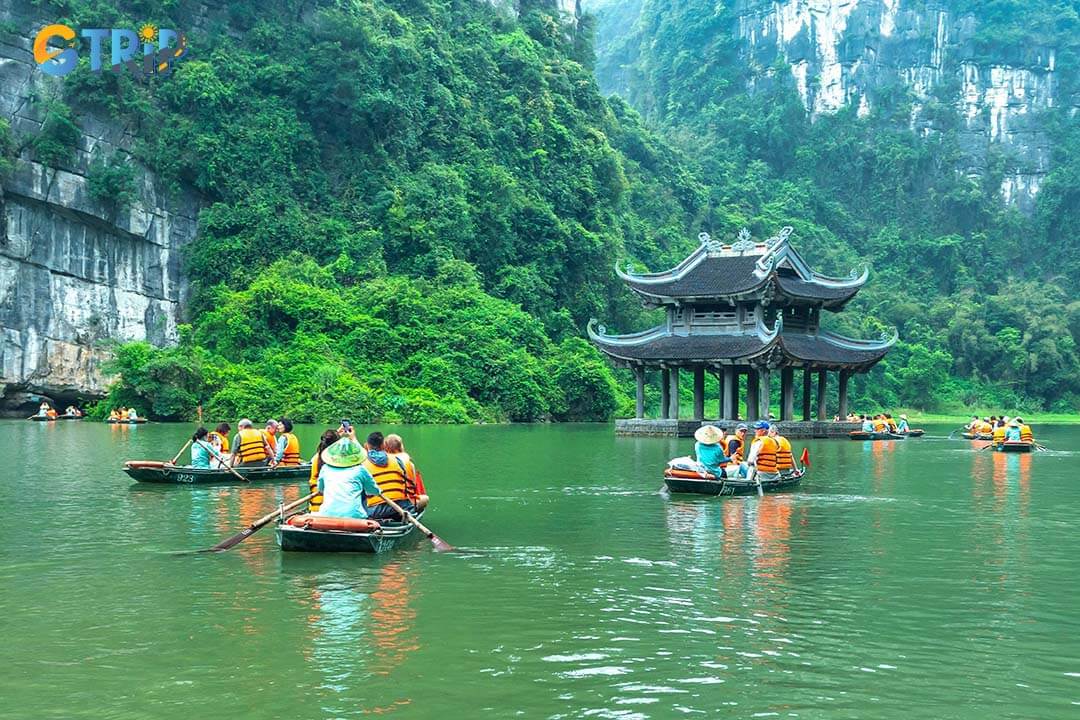 Tourists float along the Tam Coc River by boat