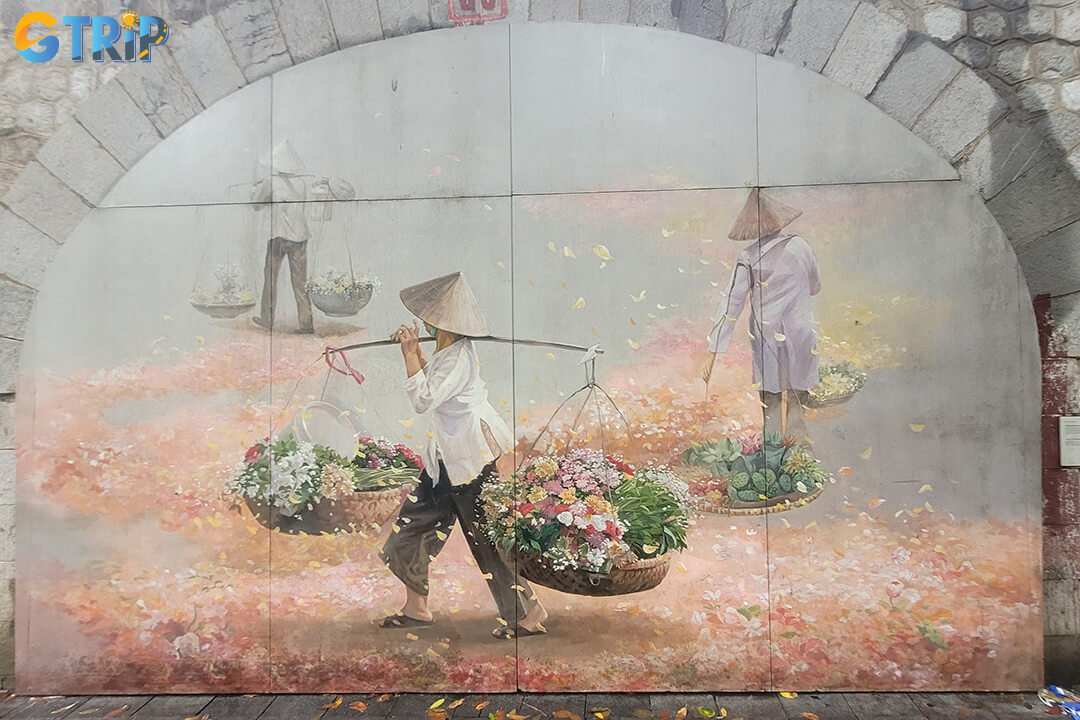 Phung Hung Mural Street features vivid murals on wooden-style surfaces, portraying Hanoi’s nostalgic scenes like lion dances, street vendors, and old water pumps