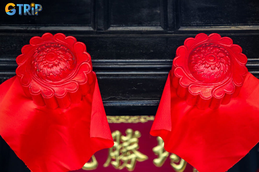 The entrance features symbolic wooden “door eyes” and removable panels that reflect traditional beliefs and the flexible design of Hoi An merchant houses