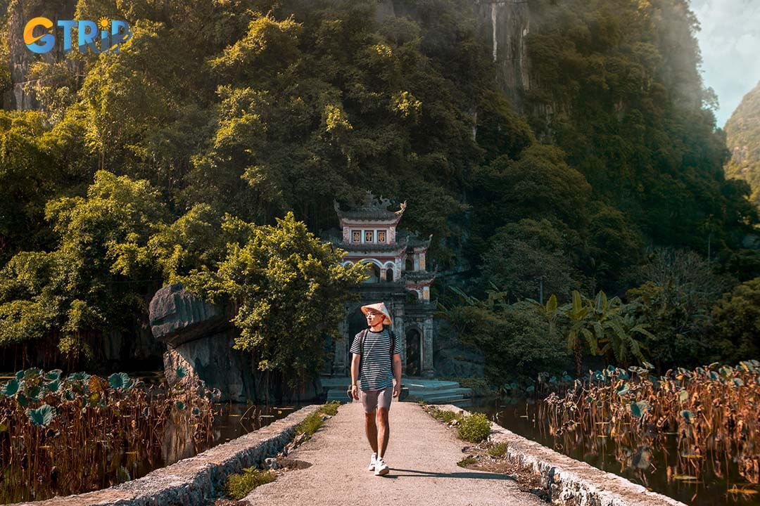 Touristman is wearing non la with backpack and sightseeing at beautiful landscape in Ninh Binh